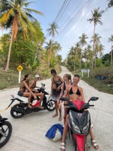 Tourist riding scooter on palm-lined road in Goa